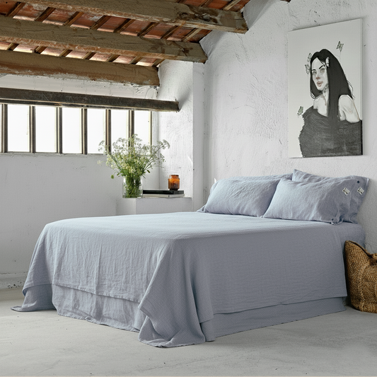 Juego de sábanas de lino en una cama con paredes blancas encaladas