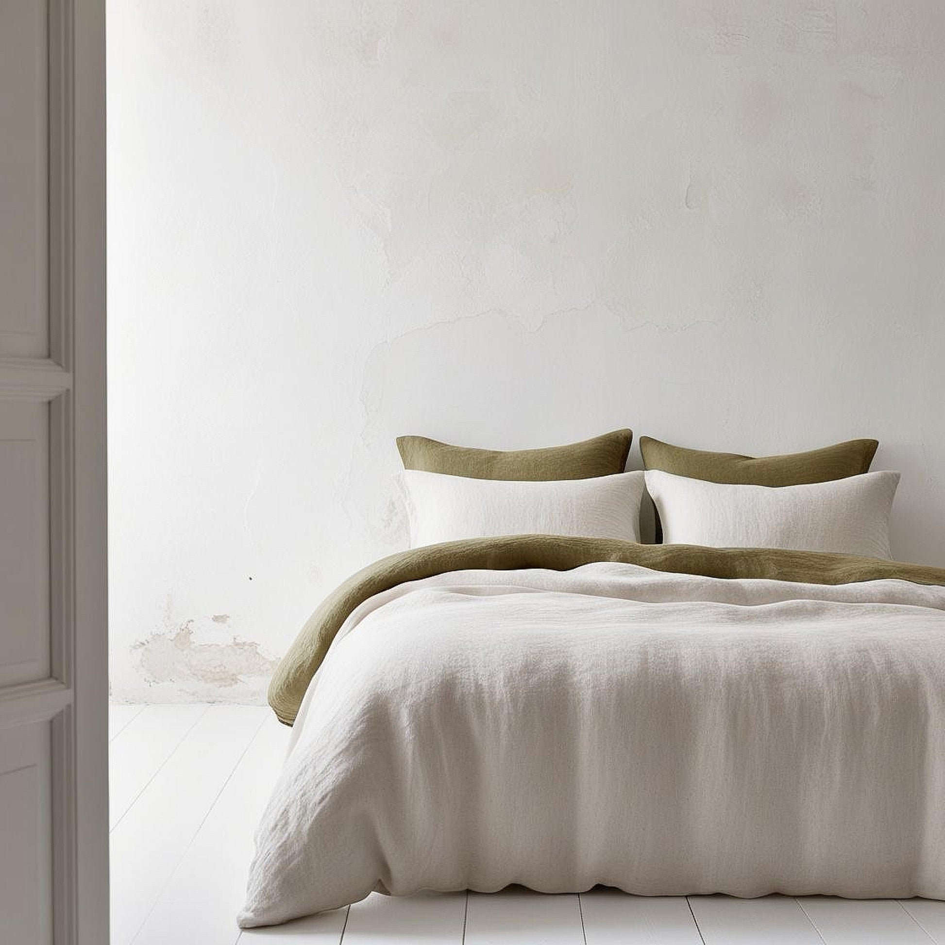 Juego de lino blanco y verde olivo sobre pared pared blanca de yeso.