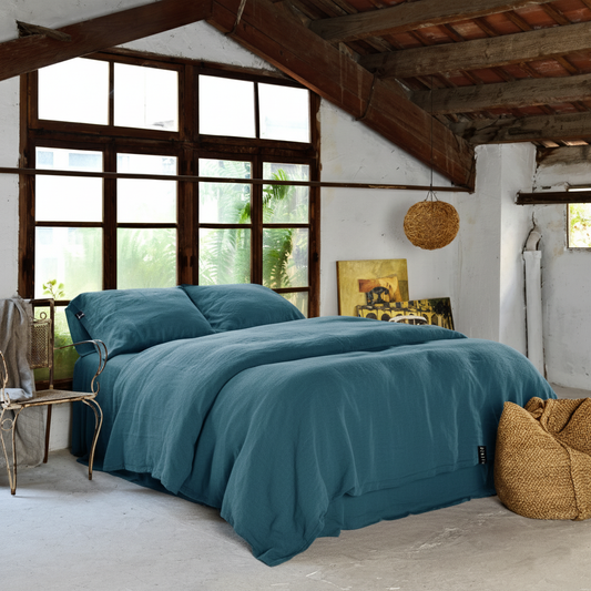 Juego de cama de lino azul tahitian. Habitación rústica con ventanal de madera