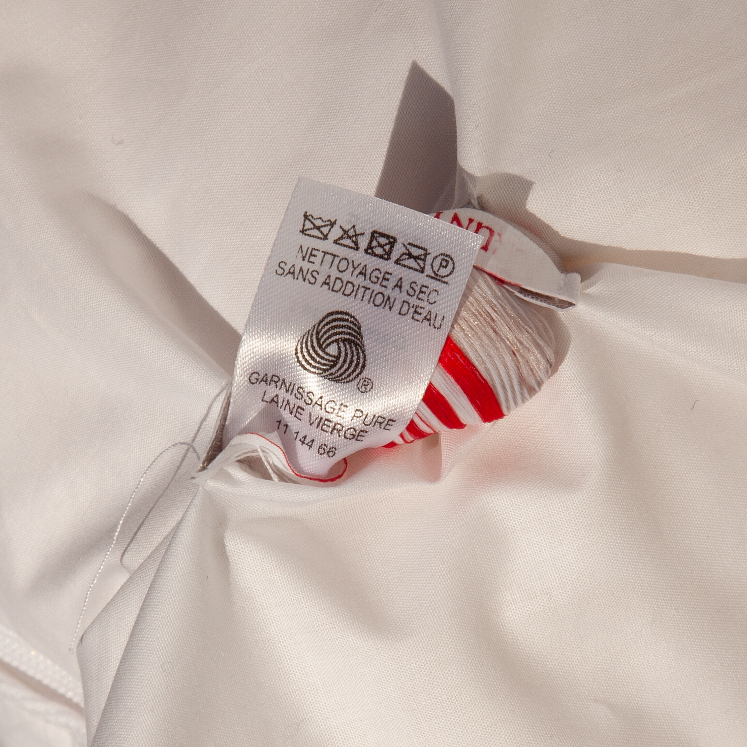 Detalle de la etiqueta oficial Woolmark en almohada de lana de los Alpes dELENZO, garantizando la pureza 