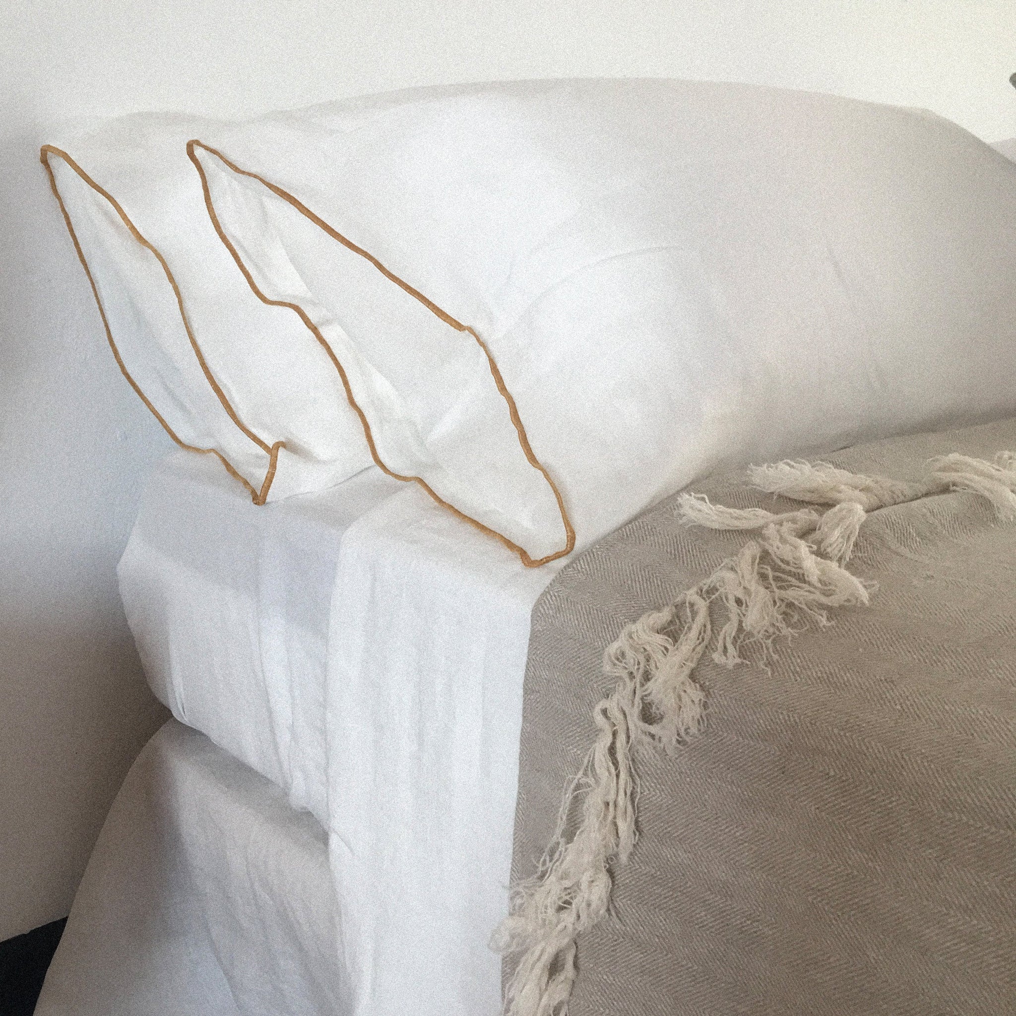Detalle de almohadas de lino blanco con ribete mostaza