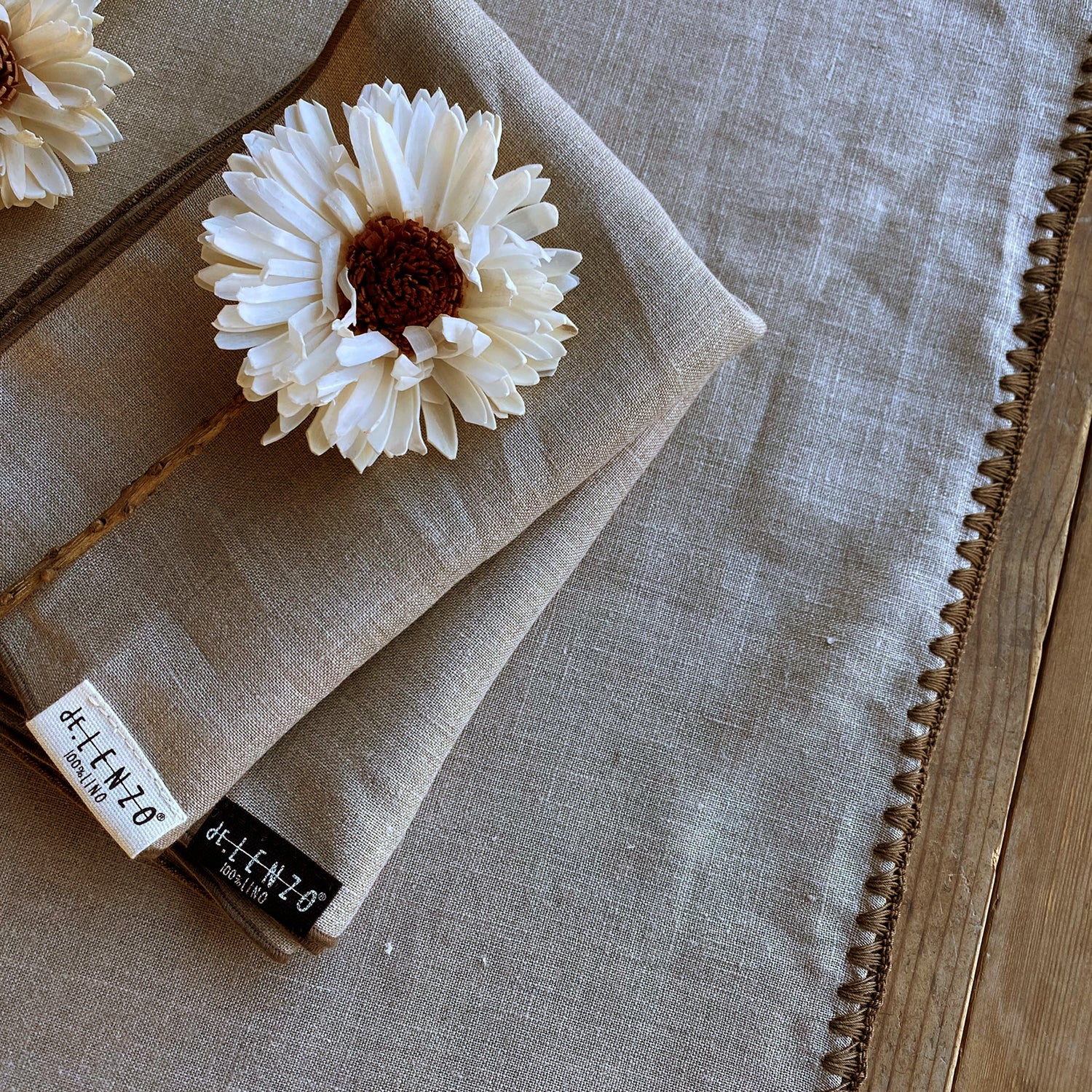 Detalle de servilletas y camino de mesa natural con flor blanca seca.