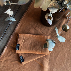 Camino y servilletas de lino con hojas secas y mesa de madera.