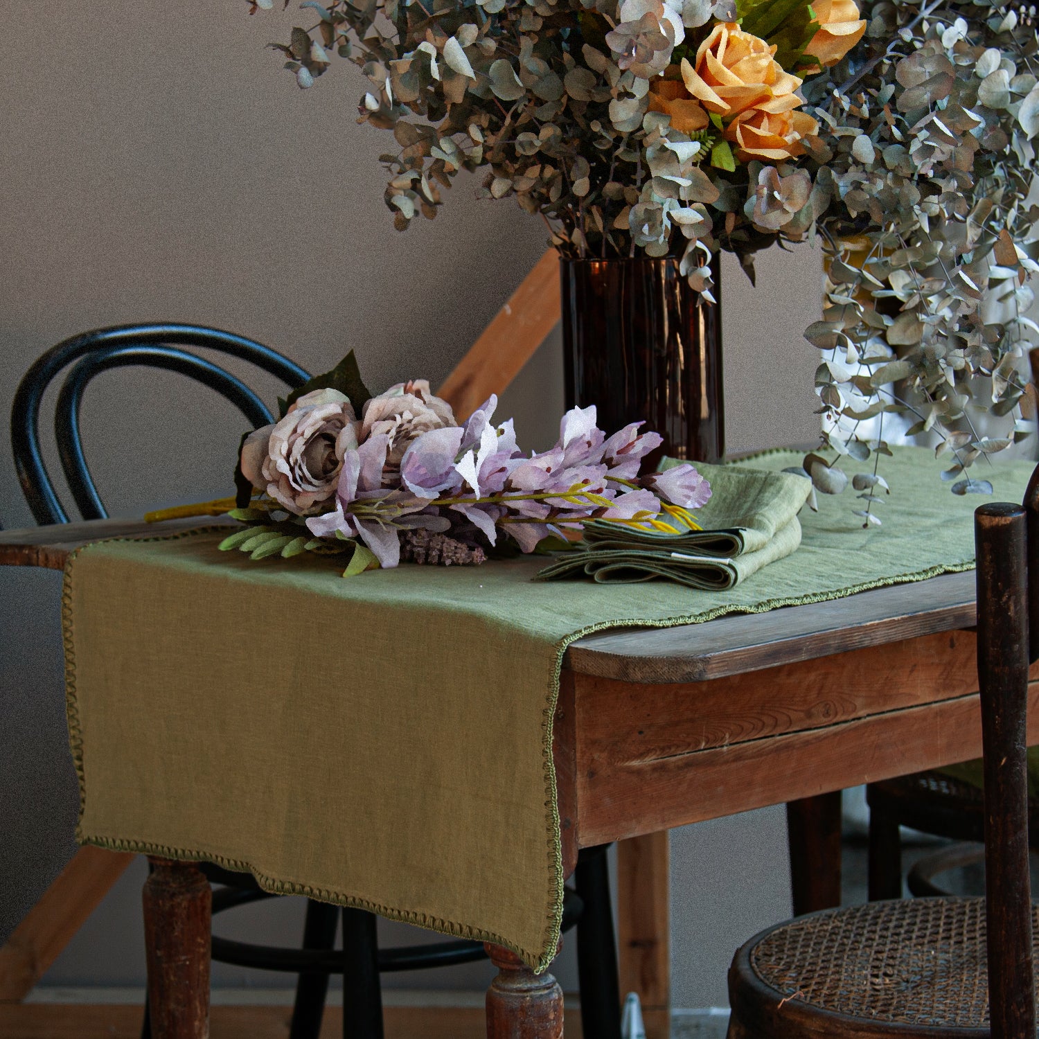 Imagen del camino de mesa verde con flores secas. Verde olivo y sus servilletas.