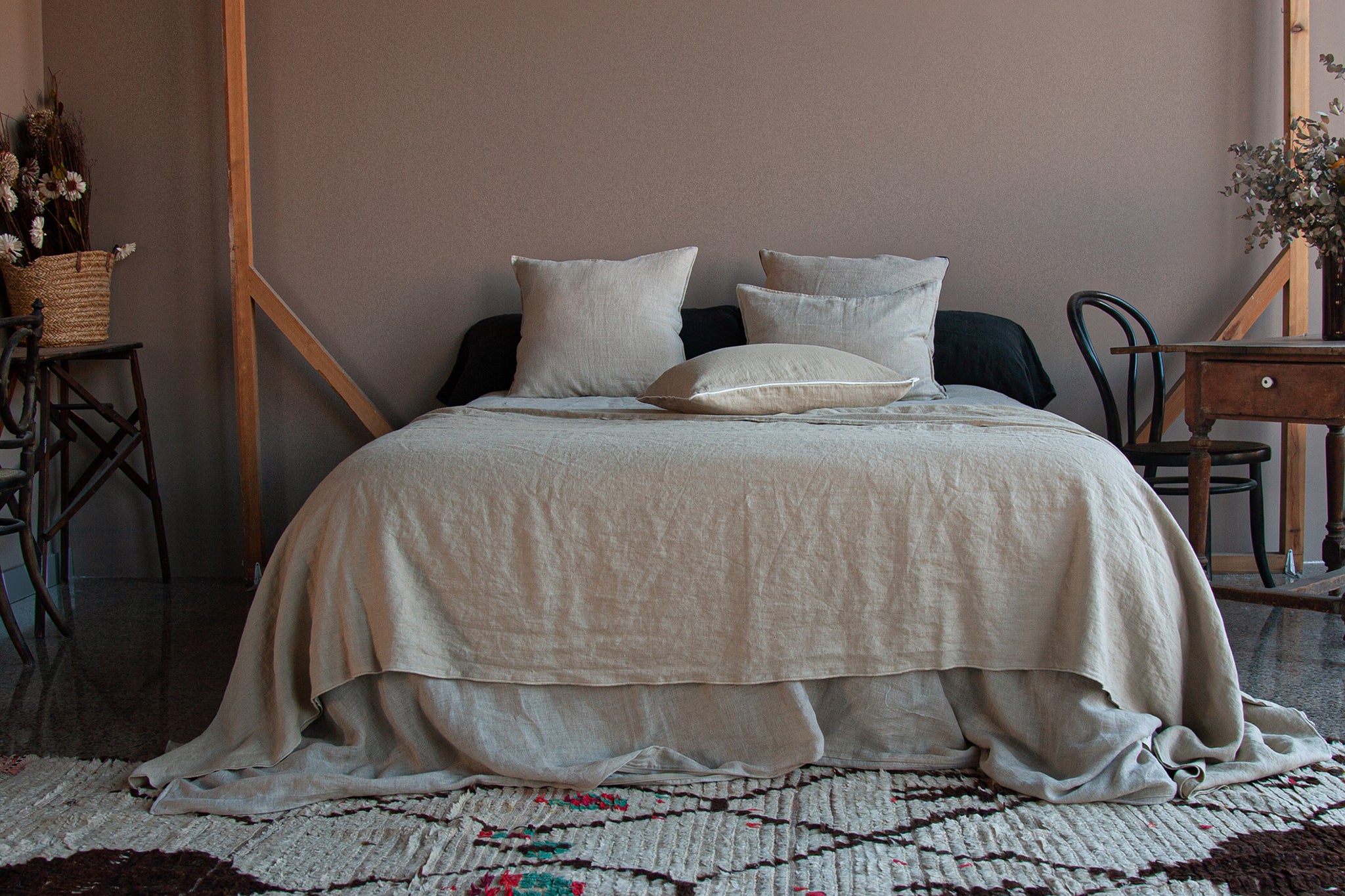 Colcha de lino de color arena, sobre cama vestida de lino natural.