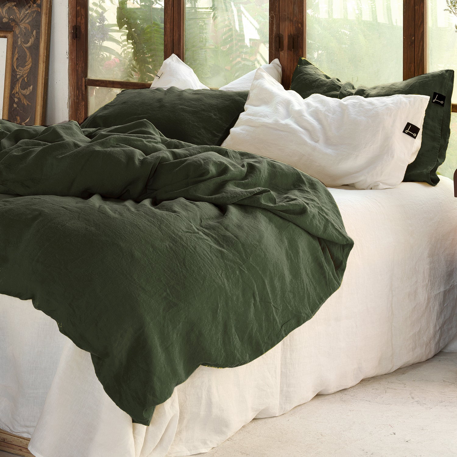 Funda nórdica de lino verde oscuro en cama con sábana blanca.