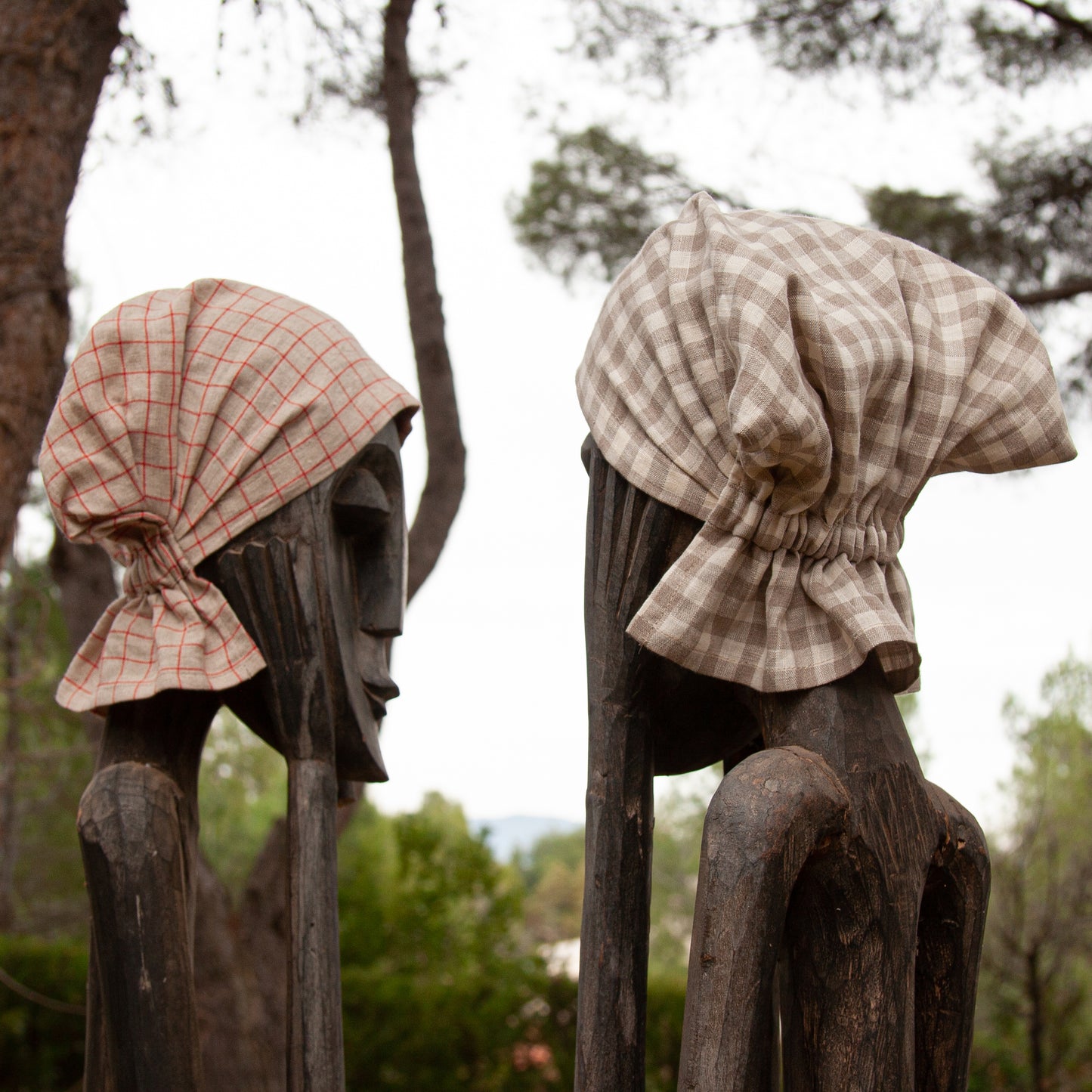 FIGURAS DE MADERA EN JARDÍN CON GORROS DE LINO