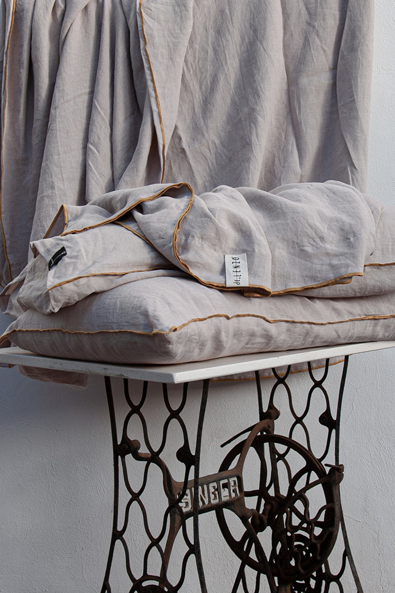 Juego de cama de lino malva sobre maquina de coser Singer. Todo con repulgo mostaza.