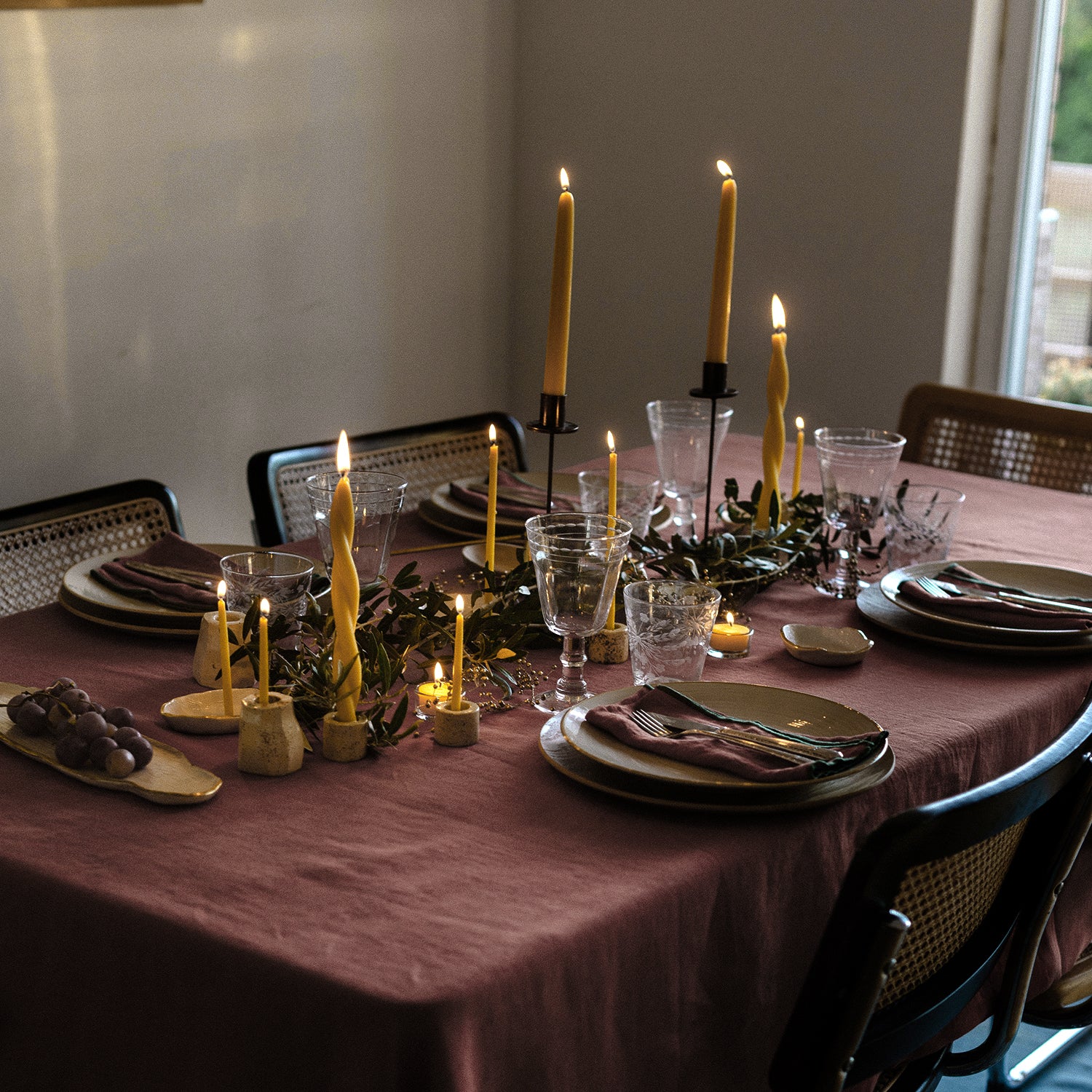 mesa con decoración navideña, velas amarillas y platos cerámicos.