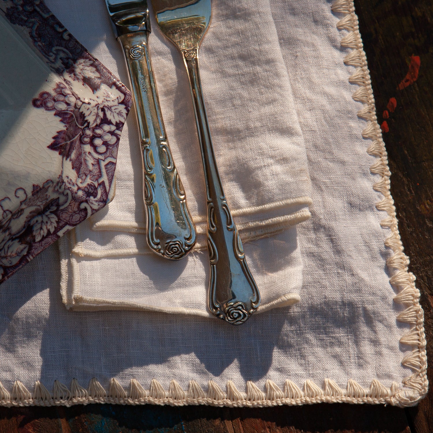 Detalle de servilleta de lino blanco con repulgo sobre individual marieta.