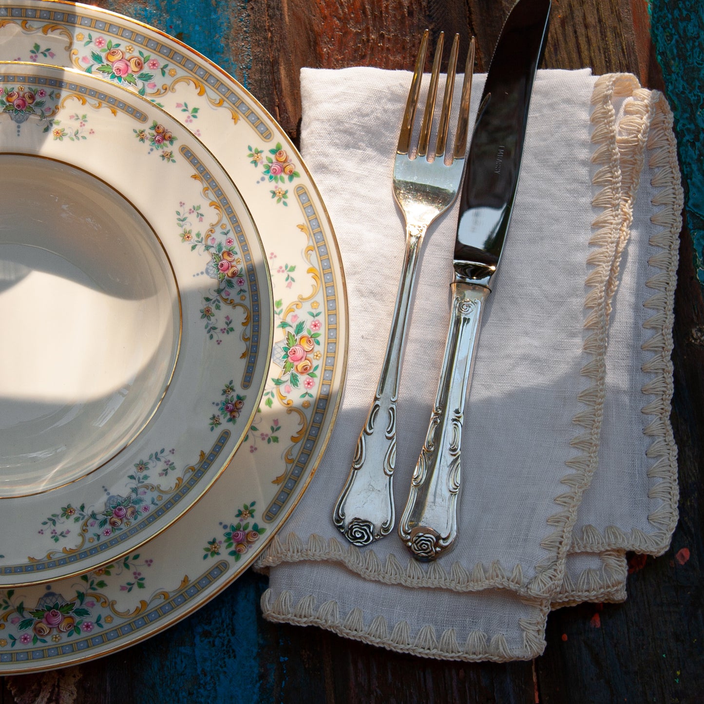 Servilleta de lino blanca y cubiertos de plata acompañados de vajilla Alemana.