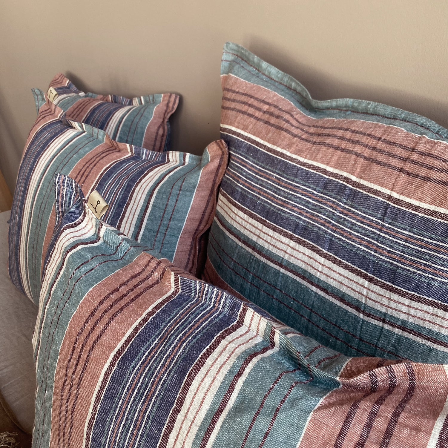 Detalle de los cojines de lino rayado en tonos verdes, azules y tierras.