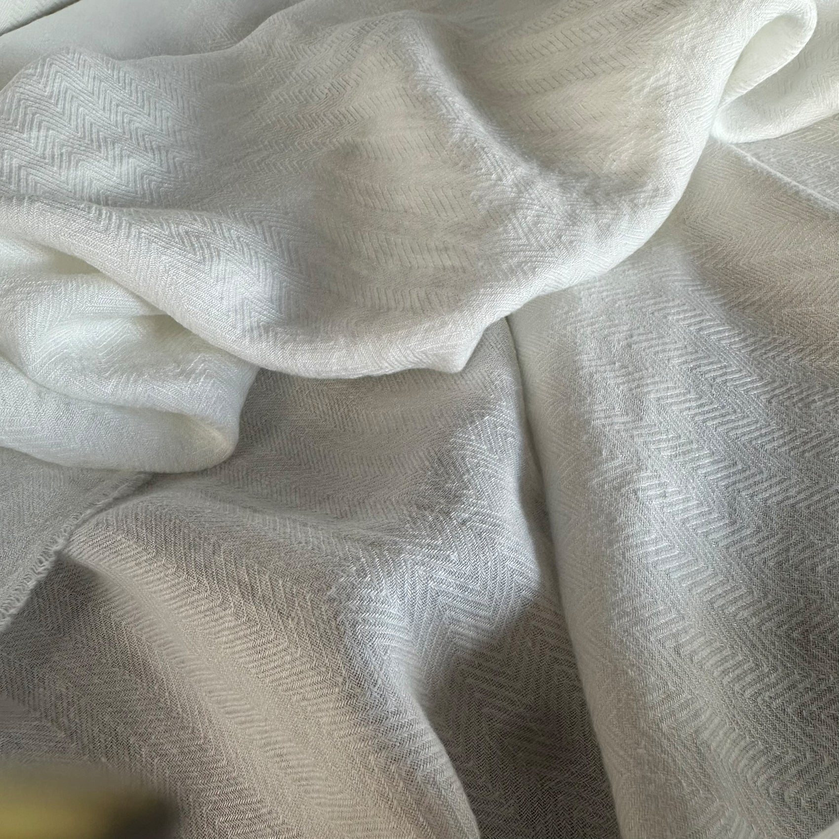 Detalle del tejido herringbone en lino espigado blanco de 200gr mostrando la suavidad y el patrón en zigzag - dELENZO