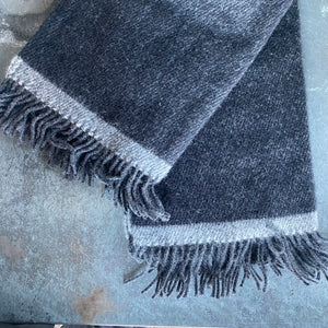 Manta de lana gris con raya gris clarita.