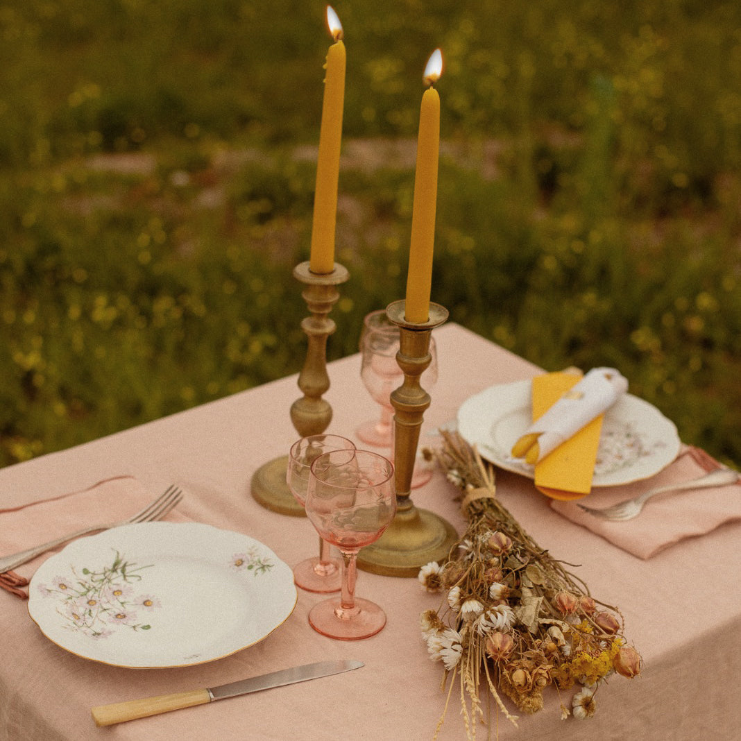 Detalle de mantel de lino rosa y velas naturales.