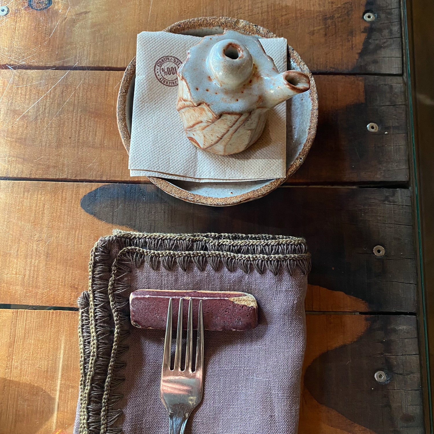 Detalle de servilleta berenjena con aceitera de ceramica.