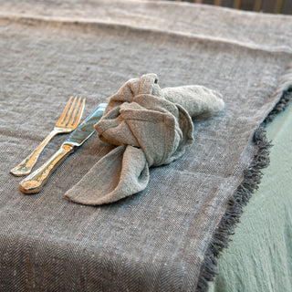 Servilleta de lino natural, cubiertos d sobre mantel verde plata y camino de mesa gris de de lino. dE.LENZO