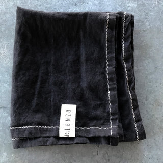 Mantel individual de lino negro con bordado marfil.