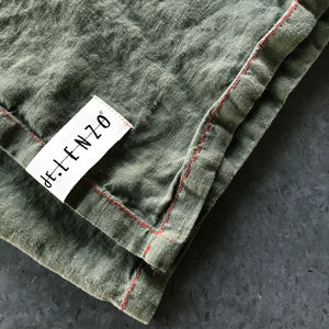 Mantel individual verde de lino lavado con detalle terracota.