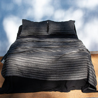 Colcha de lino plisado de color gris y negro.