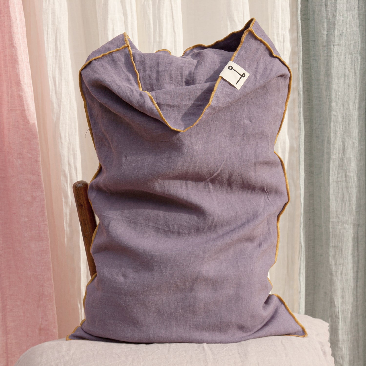 Funda de almohada de lino lila con vivo de color mostaza.