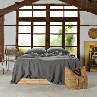 Habitación de madera con cama vestida de lino gris.