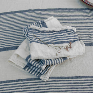 Detalle de servilletas de lino rayado azul y mantel a juego.