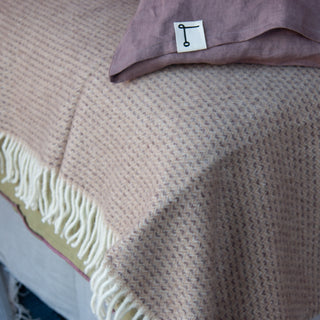Manta rosa jaspeada con morado de lana virgen Australiana.