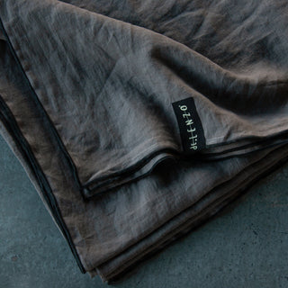 Mantel de lino gris con repulgo negro.
