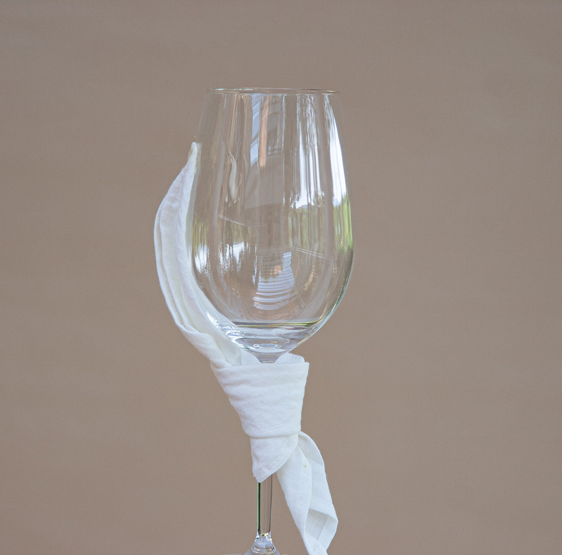 Servilleta de lino blanco de cóctel atado a copa de cristal.