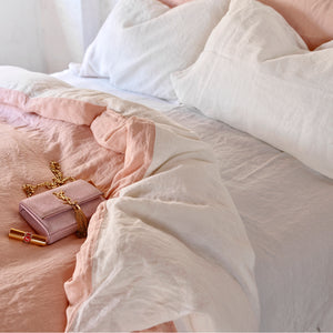 Juego de cama de lino rosa y blanco y bajera blanca.