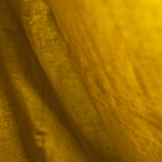 Detalle de Sábana bajera de lino de color mostaza.