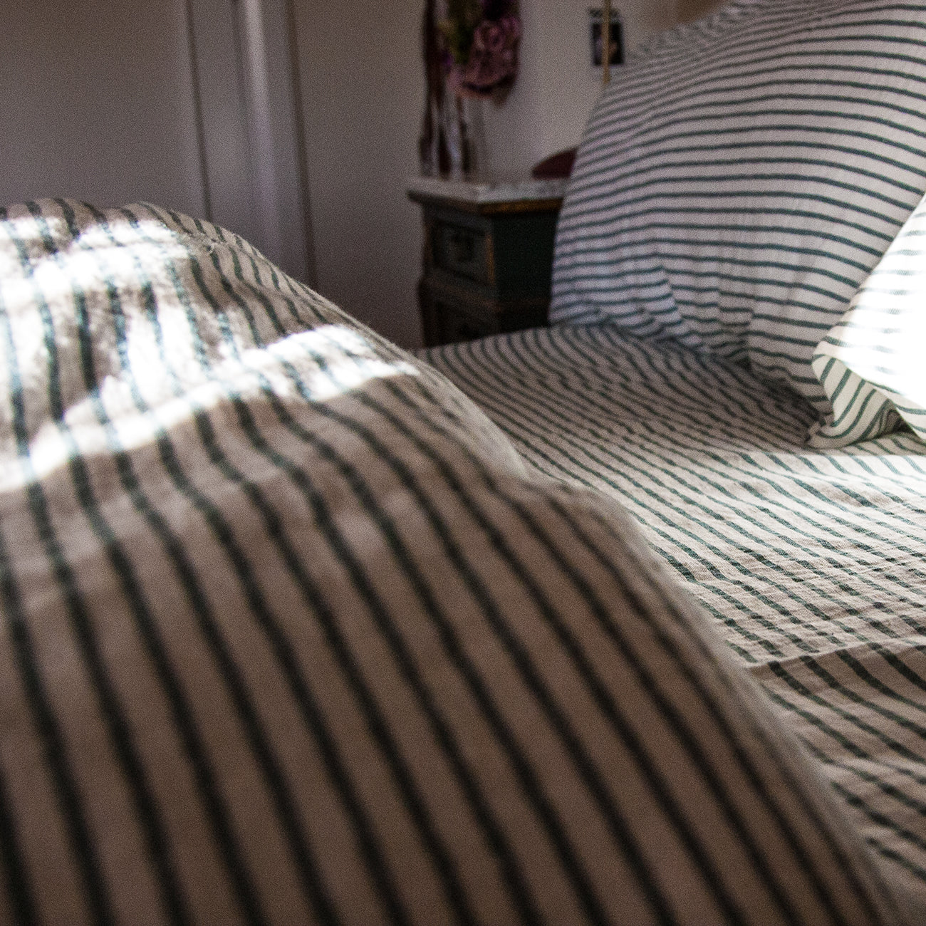 Detalle de juego de cama de lino verde rayado.