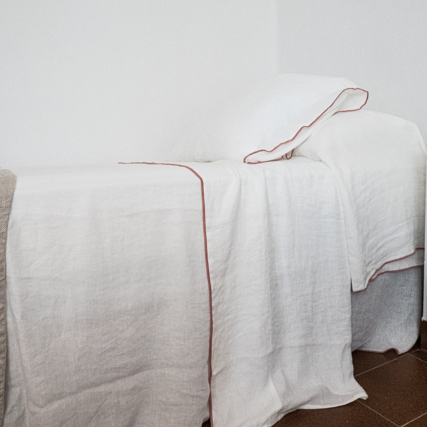 Detalle de sábanas con repulgo de color sobre lino blanco.
