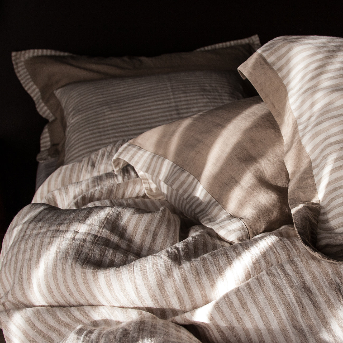 Detalle de sábanas rayadas de lino natural y blanco roto.
