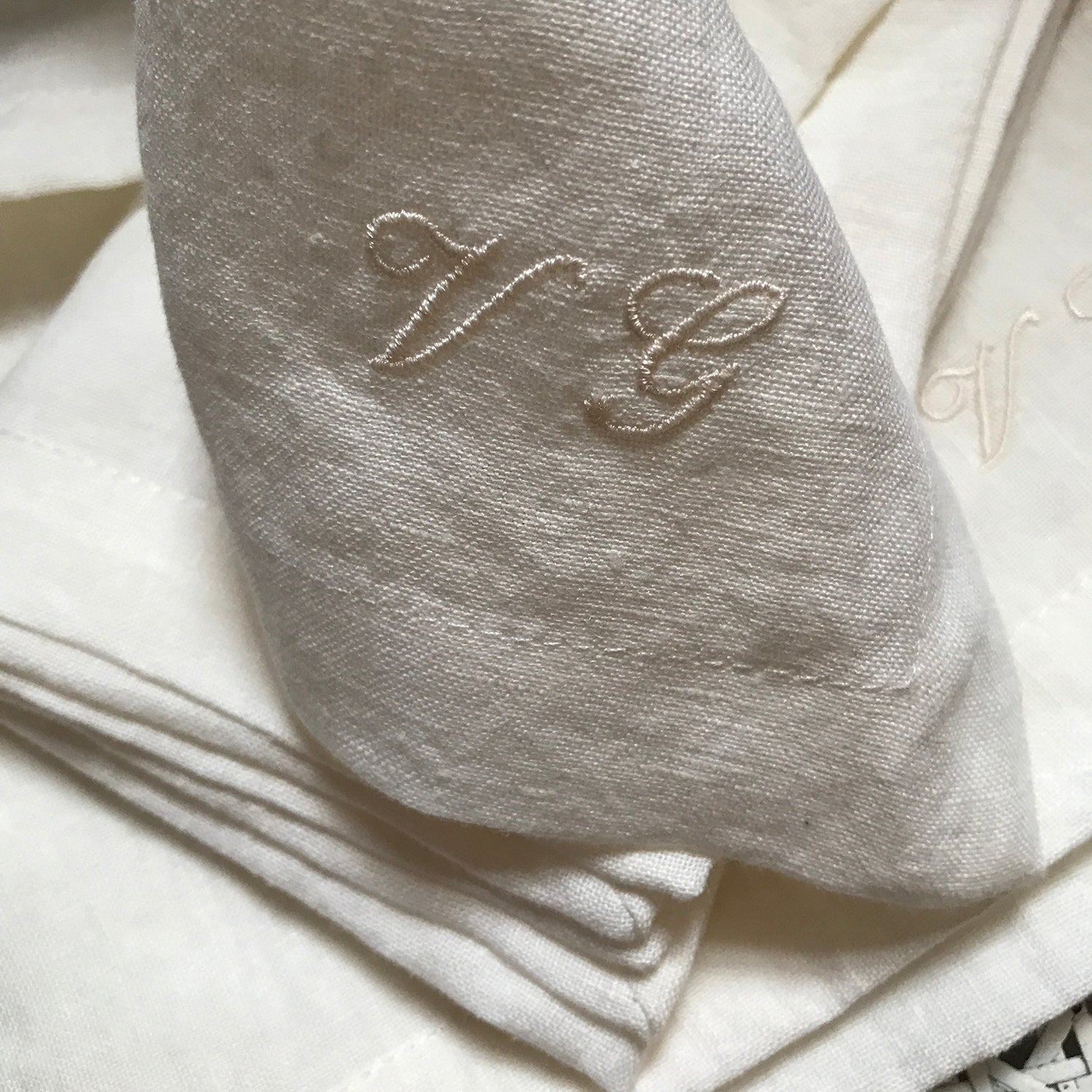 Detalle bordado en servilleta de lino blanco roto.